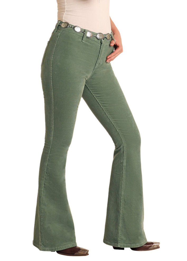 Woman wearing green flared jeans and a brown hat on a white background