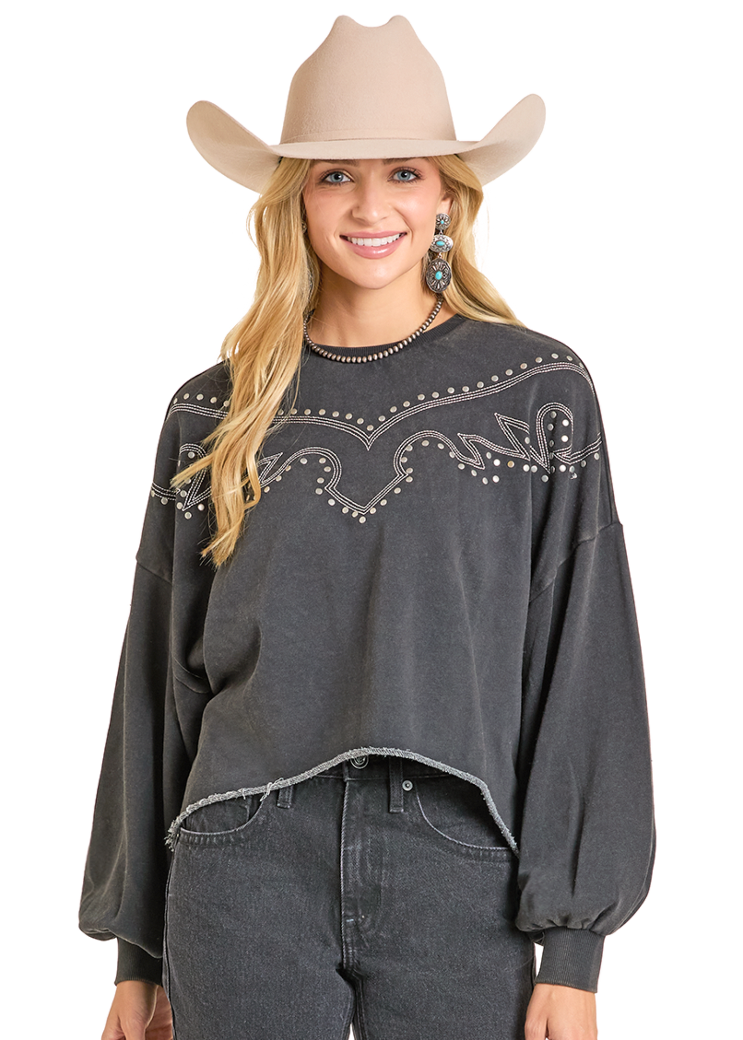 Woman wearing a dark gray long-sleeve top with embellishments and a beige cowboy hat on a white background