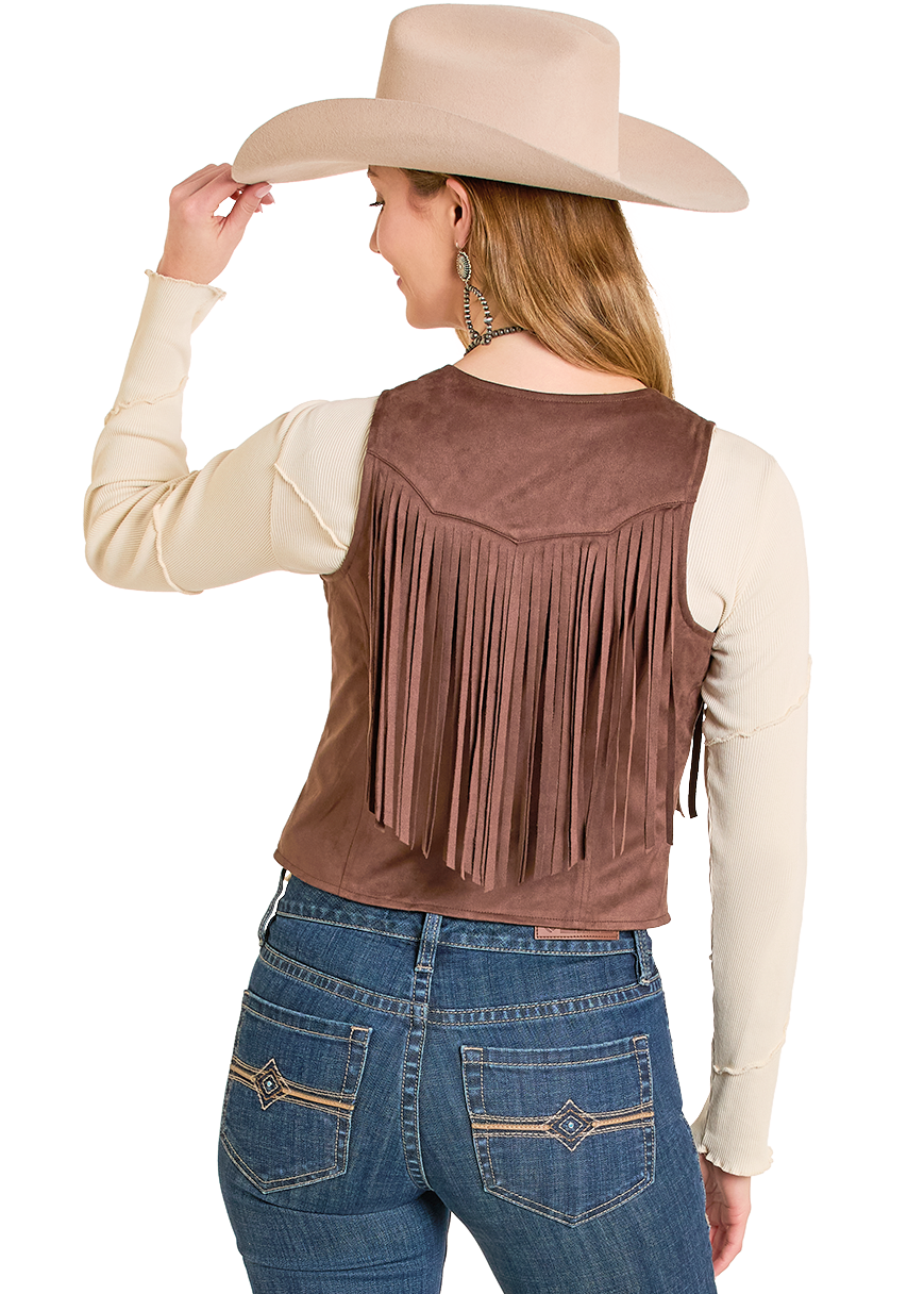 A woman is shown from the back, touching her hat and wearing a beige cowboy hat, cream long-sleeve top, blue jeans with decorative stitching, and a Rock & Roll Denim Studded Fringe Microsuede Vest.