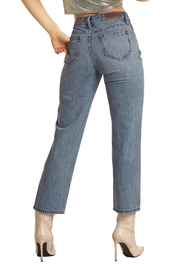 Woman wearing a black cowboy hat, silver top, and blue jeans on a white background