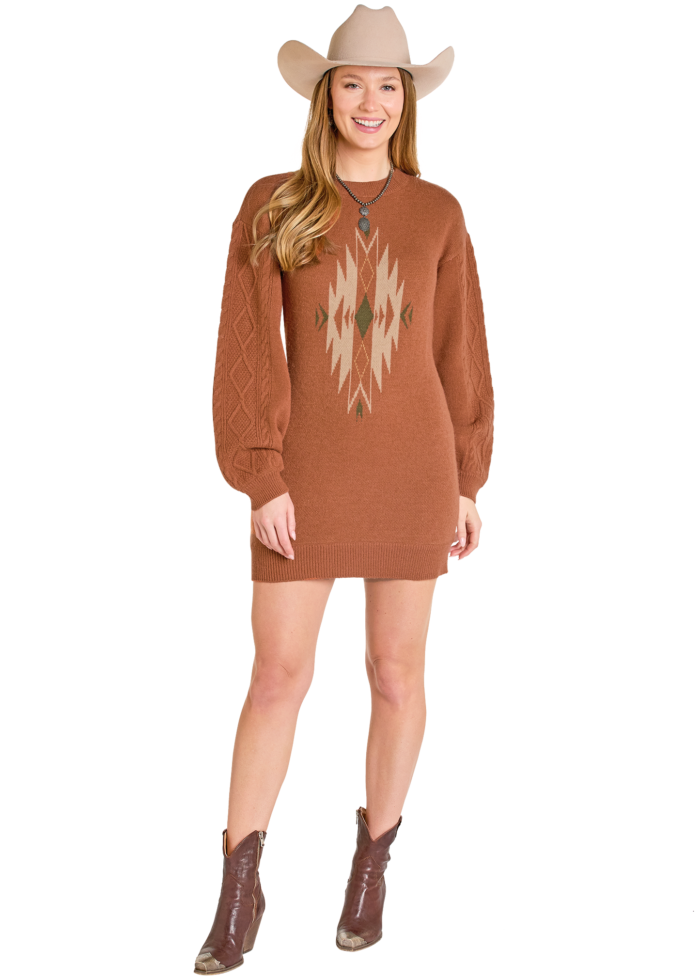 A woman in a Rock & Roll Denim Aztec Sweater Dress, tan cowboy hat, and brown boots stands smiling against a white background, highlighting cozy style.