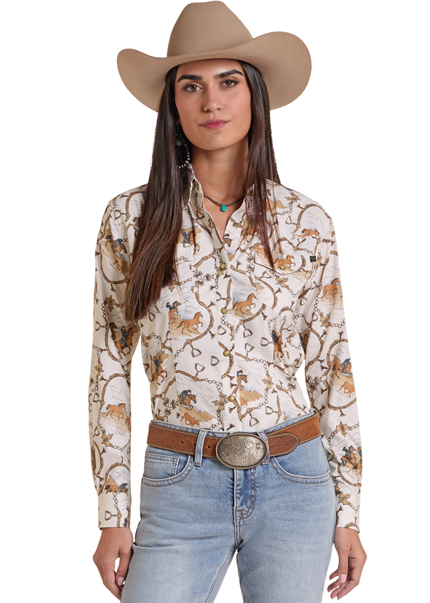 A woman modeling a western-style outfit featuring a cream long-sleeve button-down shirt with a brown and tan animal print, light-wash blue jeans, a brown belt with a large silver buckle, and a tan cowboy hat, set against a plain white background.