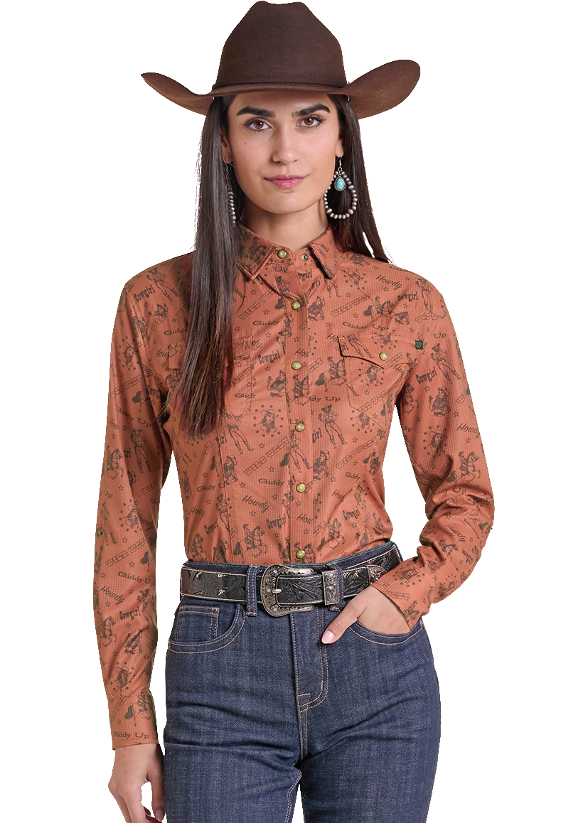 A woman modeling a western-style outfit consisting of a rust-orange long-sleeve shirt with a black floral pattern, dark blue jeans, a black belt with a silver buckle, and a brown cowboy hat, set against a plain white background.