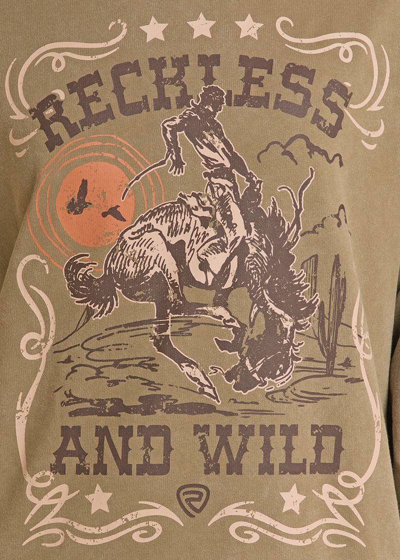 A close-up of a graphic t-shirt featuring a western theme with a bucking bronco and rider, the words 'RECKLESS AND WILD' in distressed lettering, and a brown and orange sun graphic on a tan background.
