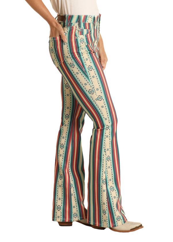 Woman wearing a white top and colorful striped pants with a cowboy hat on a white background