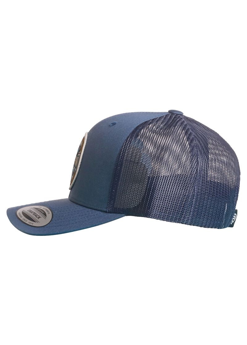 The Dale Brisby Pow Pow Cap by Rock & Roll Denim is a blue snapback with a curved brim, mesh back and sides for breathability, a solid front panel with circular patch, plus labels on the brim and side. Shown from the side.