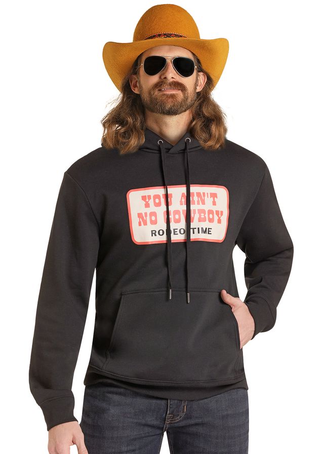 Dale Brisby wearing ablack hoodie with a pink and white graphic that reads 'YOU CAN'T NO COWBOY RODEO TIME' on the chest, paired with a yellow cowboy hat.