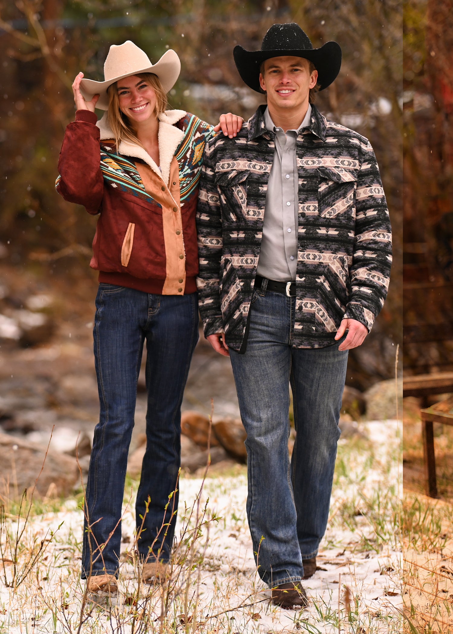 Two people stand side by side outdoors on a snowy path, smiling at the camera in classic Rock & Roll Denim style—perfect for celebrating with a Rock & Roll Denim E-Gift Card.