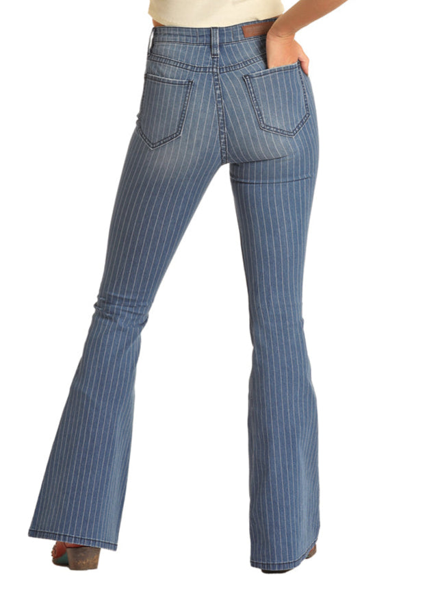 A woman stands on a white background with her left hand in her back pocket, wearing Rock & Roll Denim's Stripped Blue Button Flare Jeans.