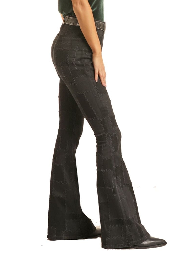 Woman wearing a black cowboy hat and black flared jeans on a white background