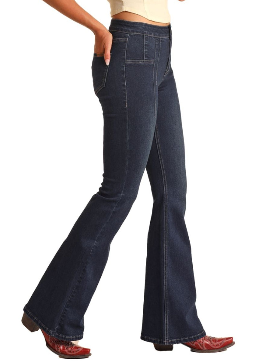 Woman wearing a beige sleeveless top, dark blue flared jeans, and a beige cowboy hat on a white background