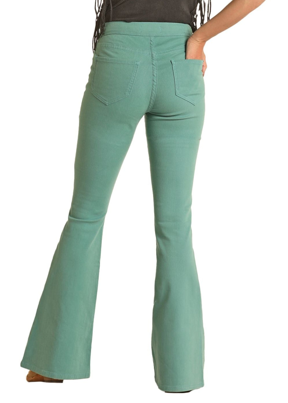 Woman wearing teal bell-bottom pants and a beige hat on a white background