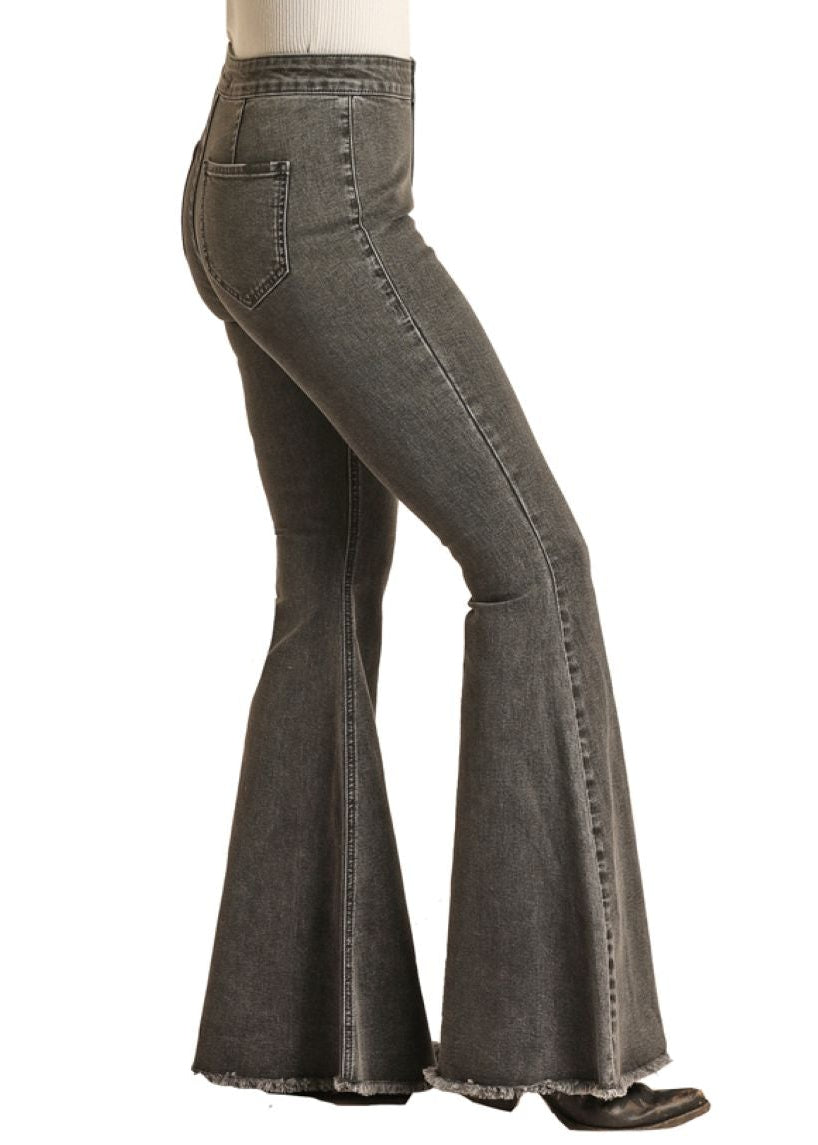 Woman wearing a black cowboy hat and gray flared jeans on a white background