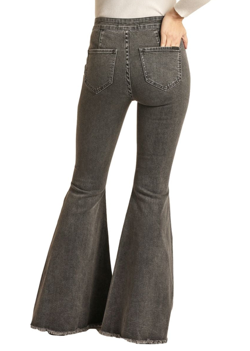 Person wearing a black hat, white top, and gray flared jeans on a white background