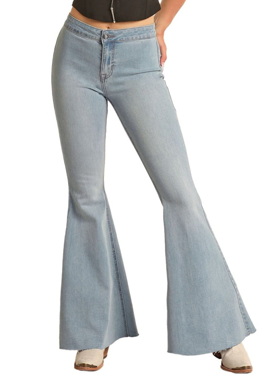 Woman wearing a black sleeveless top and light blue bell-bottom pants with a straw hat on a white background