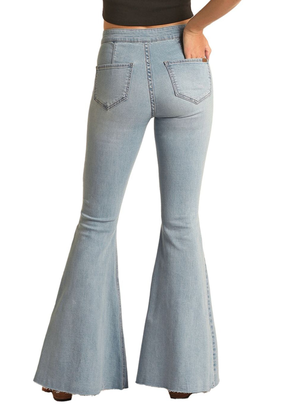 Woman wearing light blue bell-bottom jeans and a black top with a white background