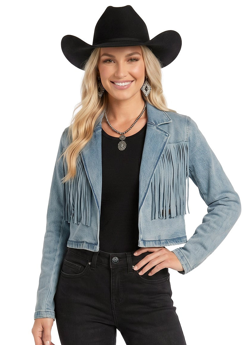 Woman wearing a denim jacket with fringe, black cowboy hat, black top, and black pants on a white background