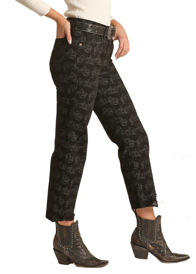 Woman wearing a white shirt, black patterned pants, and a black cowboy hat on a white background