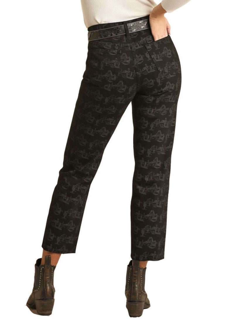 Woman wearing a white sweater, black patterned pants, and a black hat on a white background