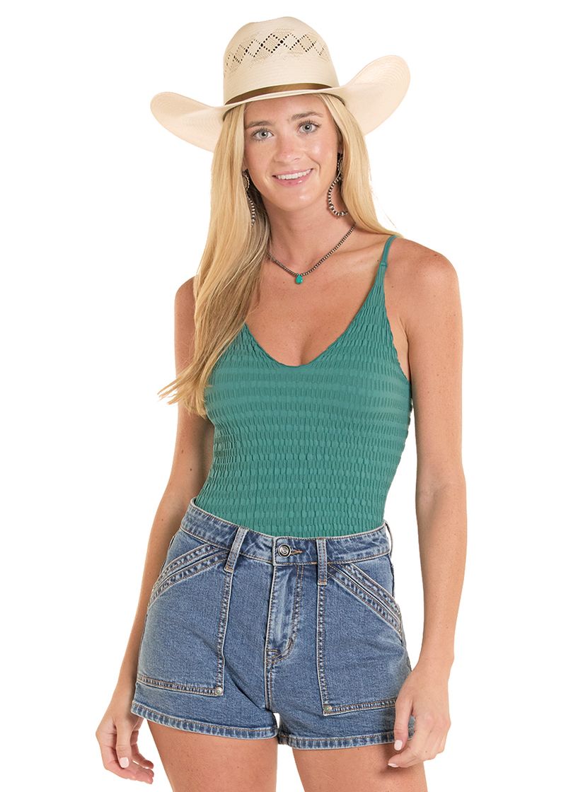 Woman wearing a green tank top and denim shorts with a cowboy hat on a white background