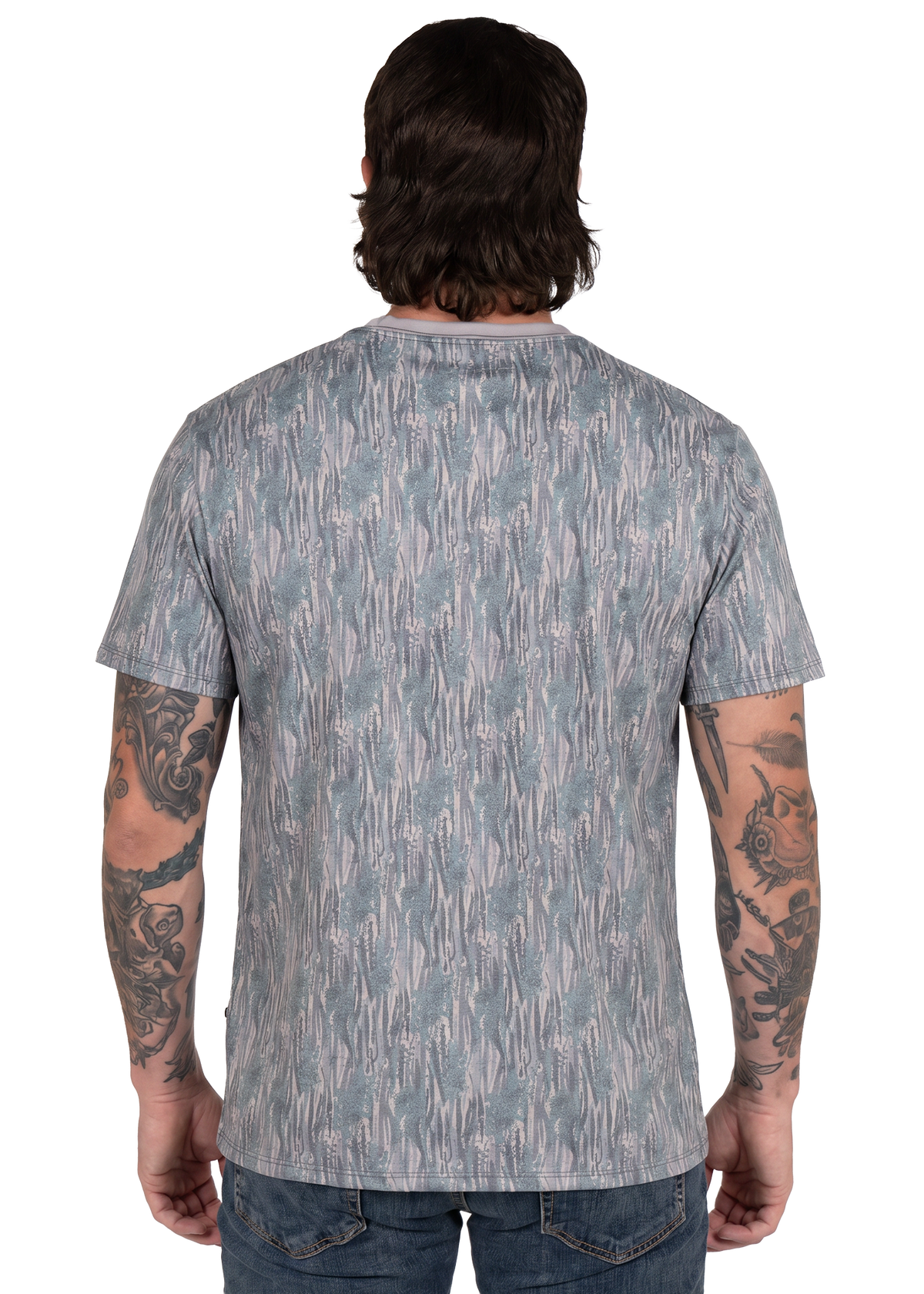 A man viewed from the back wearing a short-sleeve crewneck t-shirt with an abstract vertical brushstroke pattern in muted blue-gray and white, paired with blue jeans.
