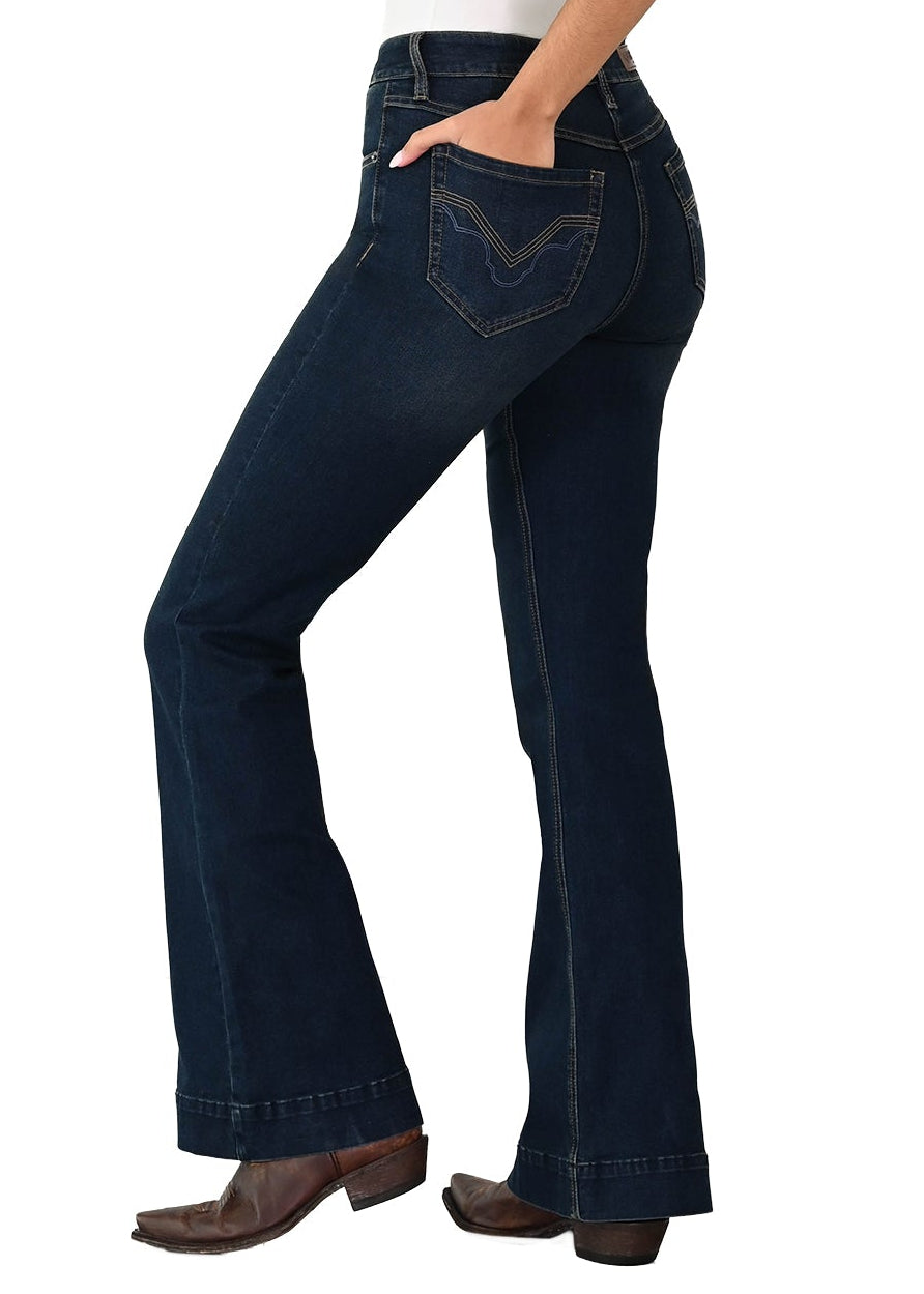 A woman modeling dark blue high-waisted flare jeans with a white tank top and a beige cowboy hat, shown from the side against a plain white background.