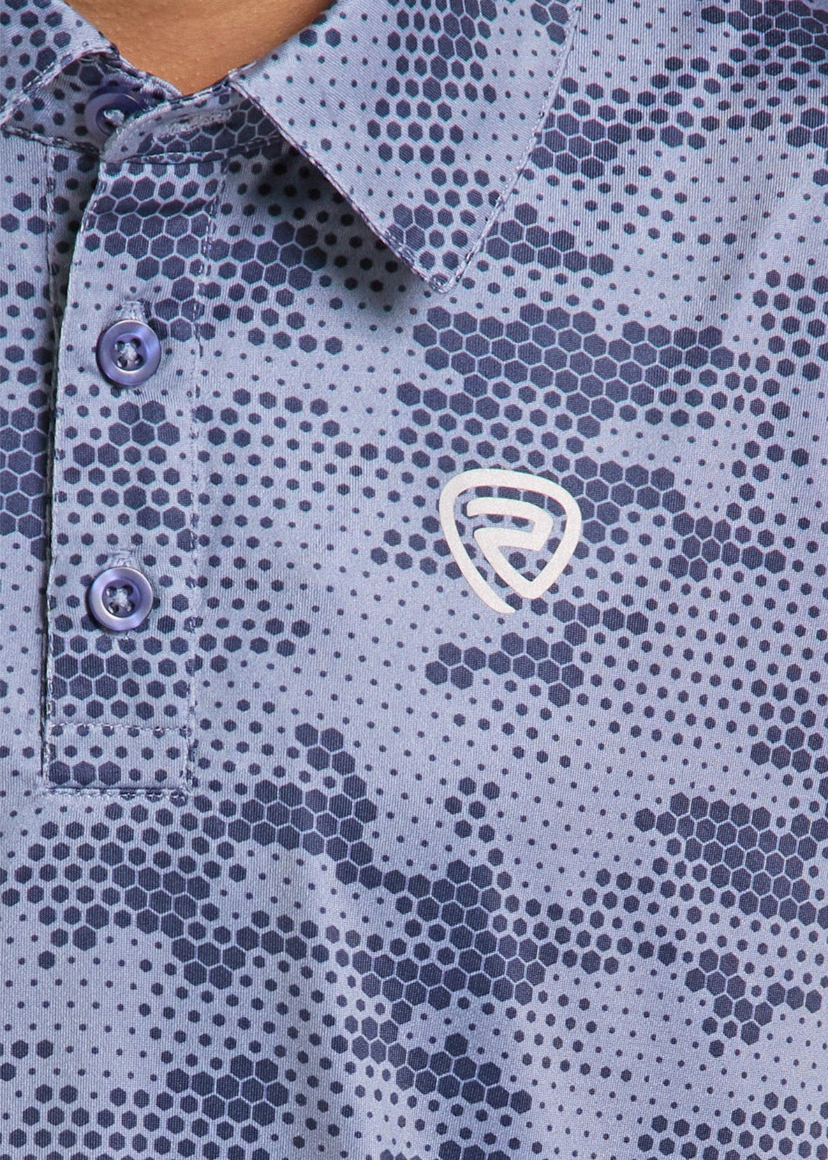 Close-up of a polo shirt featuring a blue and navy geometric hexagon pattern with a white shield logo on the chest.