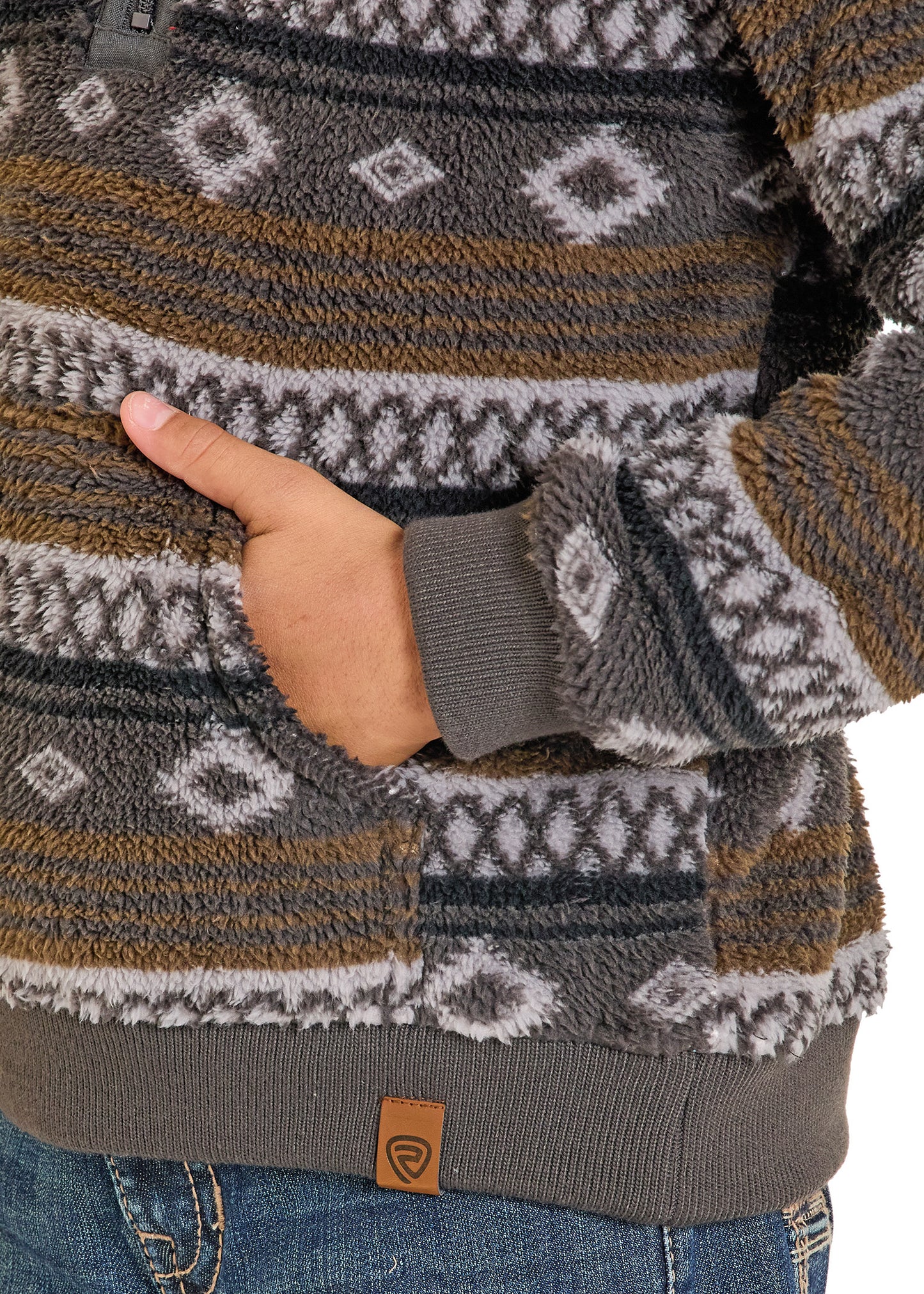 Close-up of a person wearing a patterned sweater with a hand in the pocket.