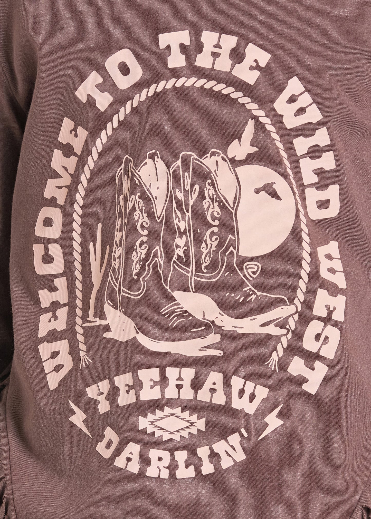 Close-up of a heathered brownish-purple graphic t-shirt featuring a western design with cowboy boots, a moon, and the text 'WELCOME TO THE WILD WEST' and 'YEEHAW DARLIN''.