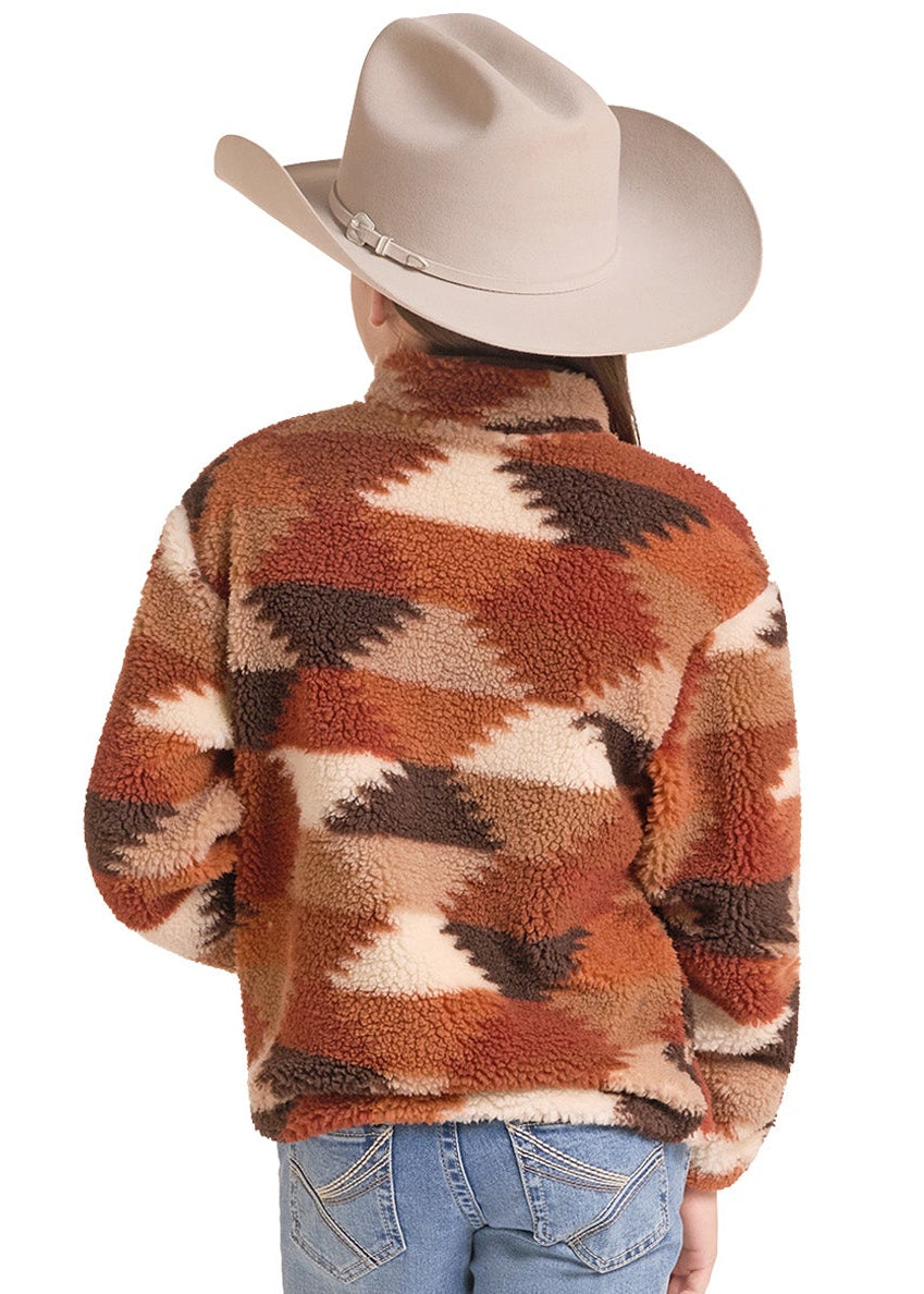 A person shown from the back wearing a sherpa fleece cropped sweater with a brown, orange, and beige geometric pattern, blue jeans.
