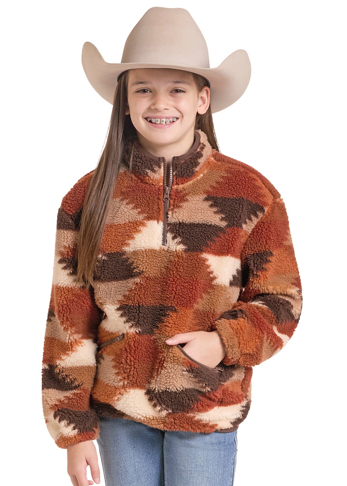 A young girl wearing a beige cowboy hat and a brown, orange, and beige patterned sherpa quarter-zip fleece pullover sweater, paired with blue jeans, against a solid white background.