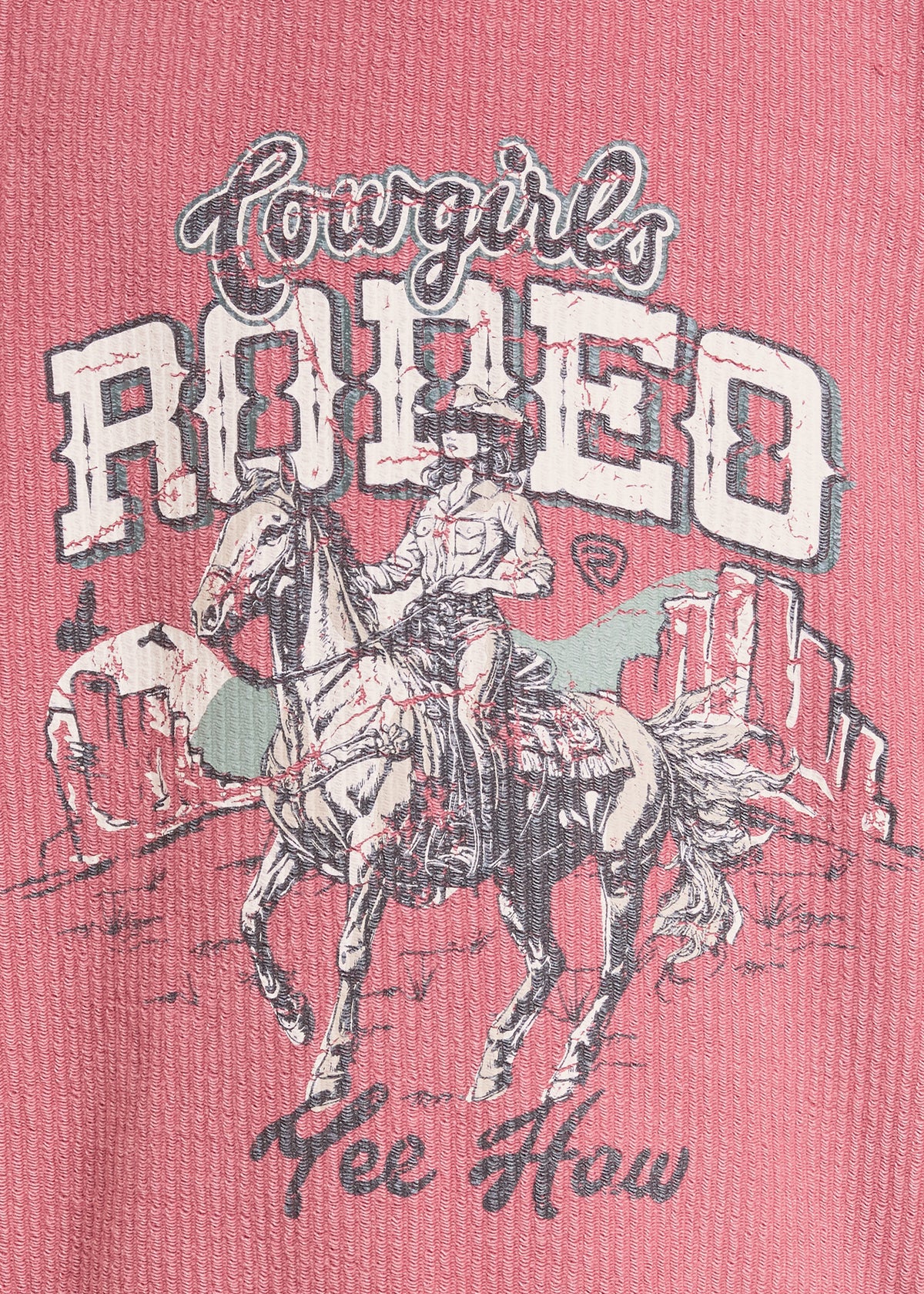 A close-up of a pink graphic t-shirt featuring a western design with the text 'Cowgirls Rodeo' and 'Lee Howard' in dark gray script, alongside an illustration of a cowboy riding a horse.