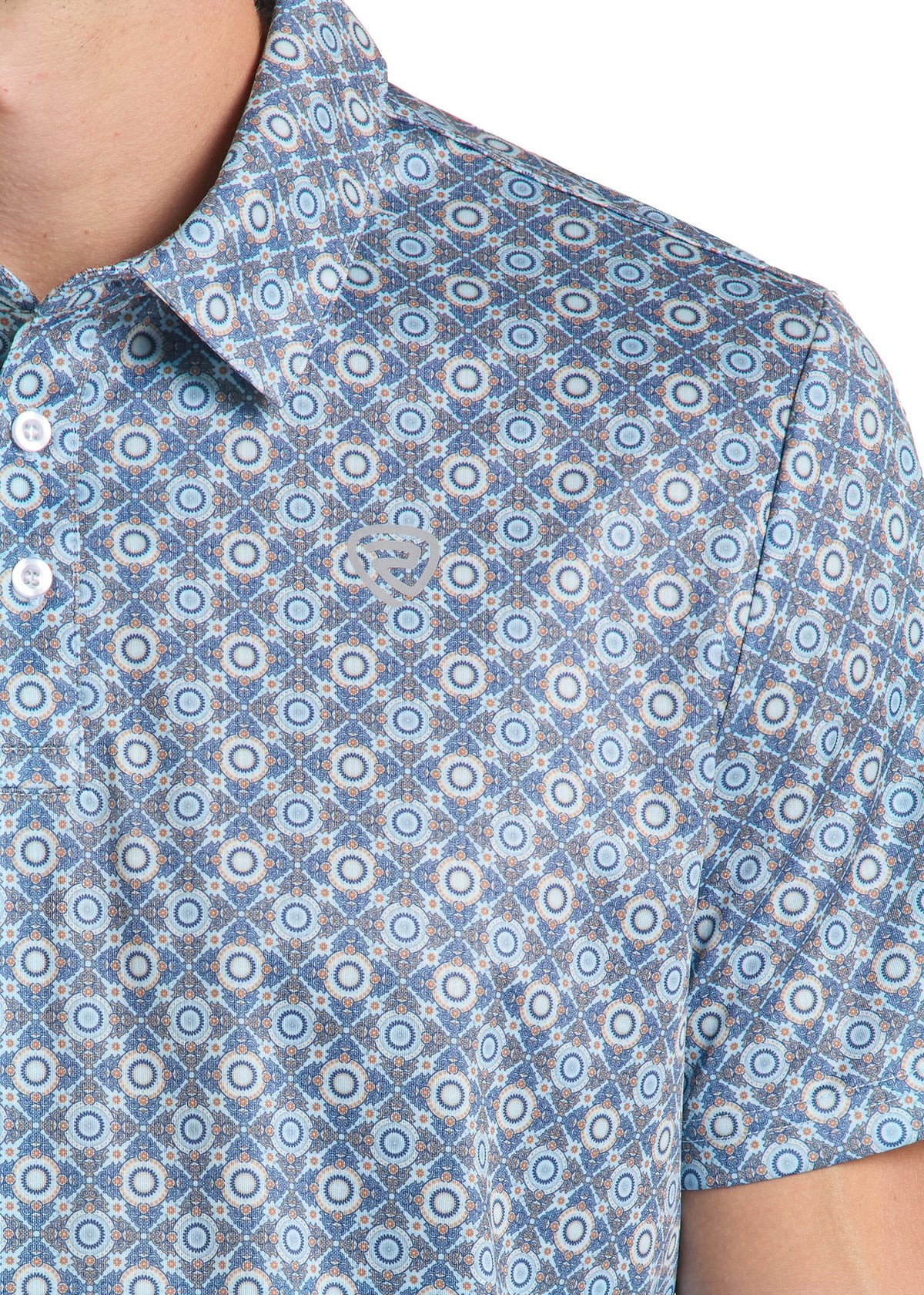 Close-up of a short-sleeve button-up shirt worn by a model, featuring an all-over geometric medallion pattern in shades of blue, white, and light gray.