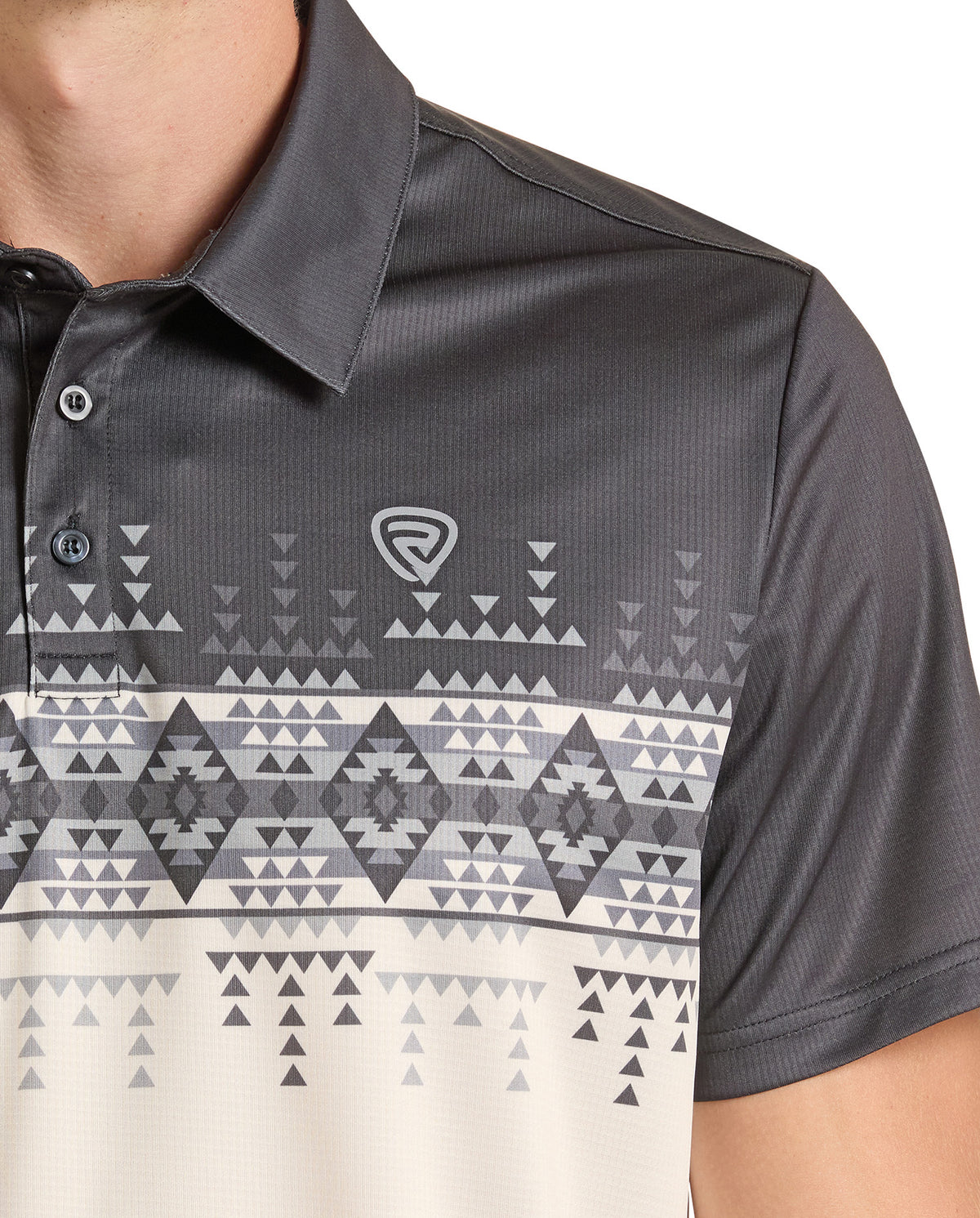 A close-up of a man wearing a dark gray short-sleeve polo shirt with a geometric tribal pattern in shades of gray and off-white. The shirt features a collar, a three-button placket, and a small shield logo on the left chest.