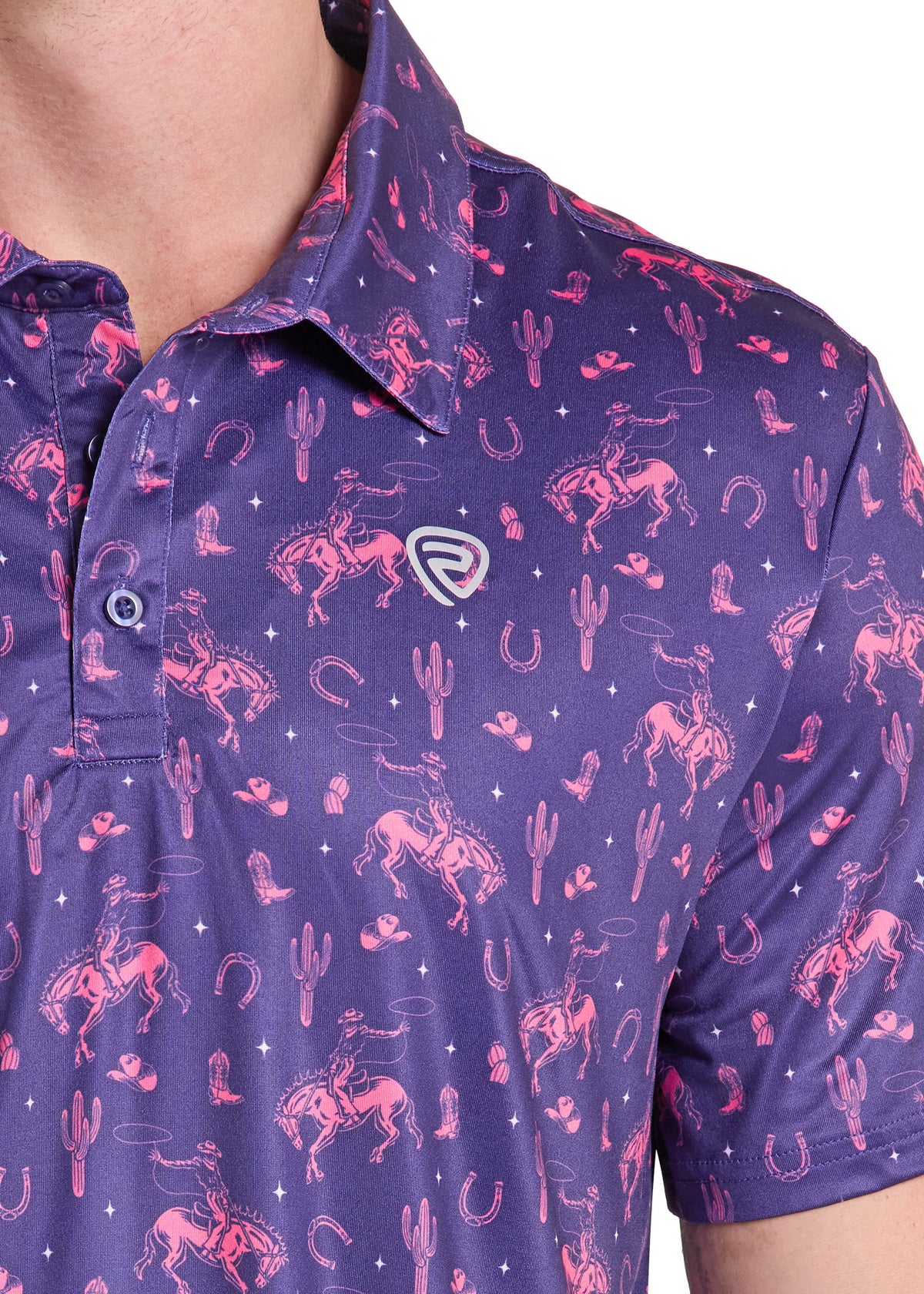 Close-up of a man wearing a short-sleeve polo shirt in purple with a pink western-themed print featuring horses, cacti, horseshoes, and stars. A small shield logo is visible on the left chest.