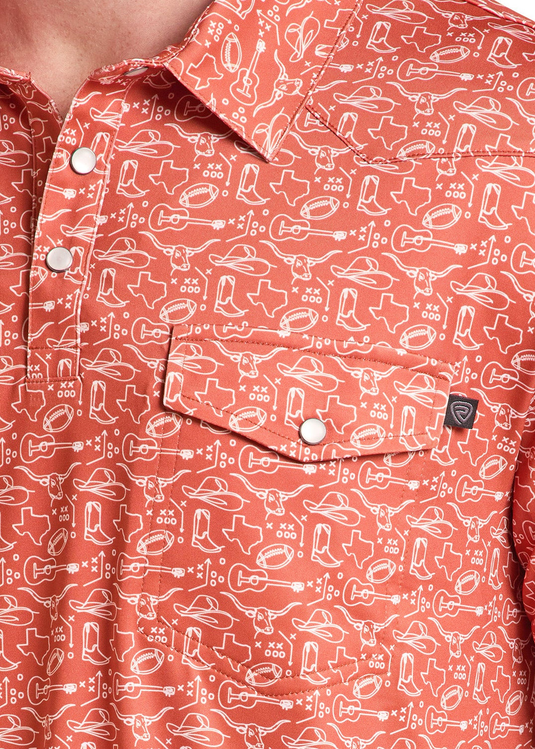Close-up of a man wearing a short-sleeve button-up shirt in a coral orange color with a white abstract pattern. The shirt features a chest pocket with a snap button and a small black brand tag.