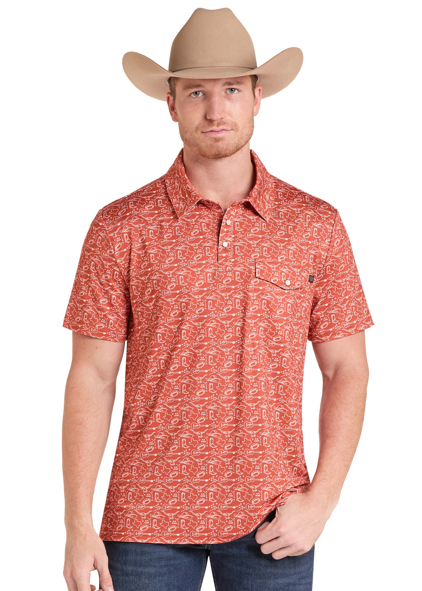 A man wearing a tan cowboy hat and a short-sleeve collared button-up shirt with an allover western-style print in rust red and beige, paired with blue jeans against a plain white background.