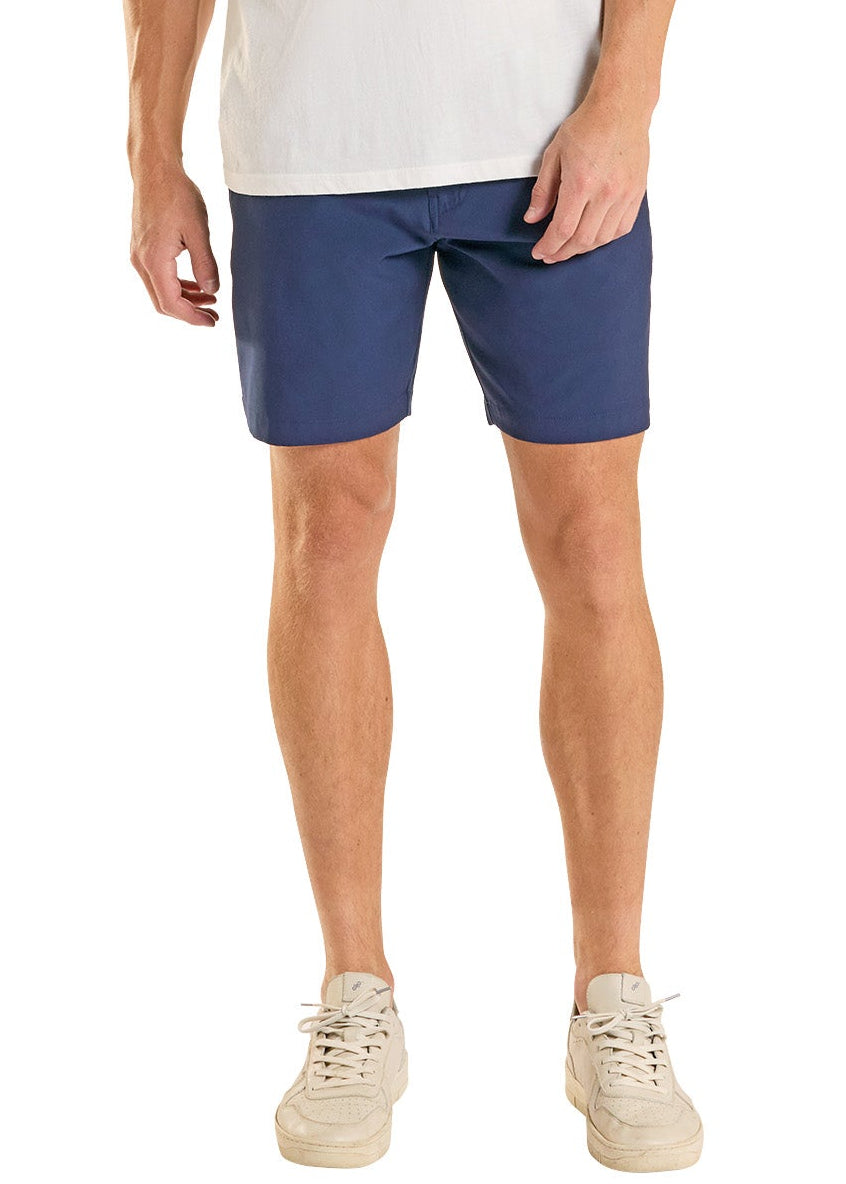 Man wearing a white t-shirt with a logo and blue shorts on a white background