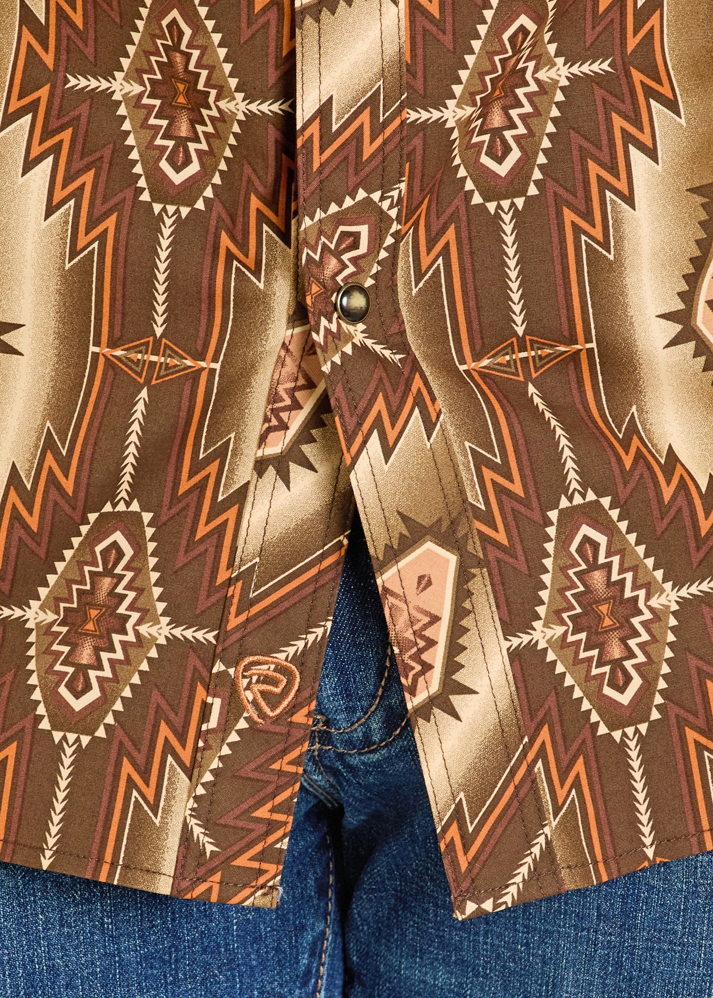 Close-up of a shirt with a detailed pattern on a blue denim background