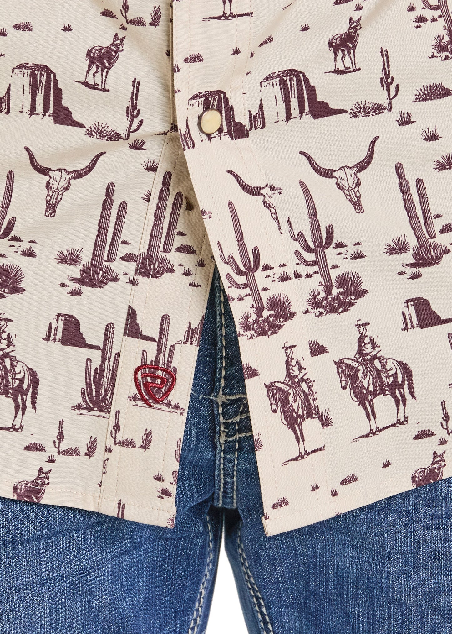 Close-up of a shirt with a desert-themed pattern featuring cacti, mountains, and a cowboy on a horse.