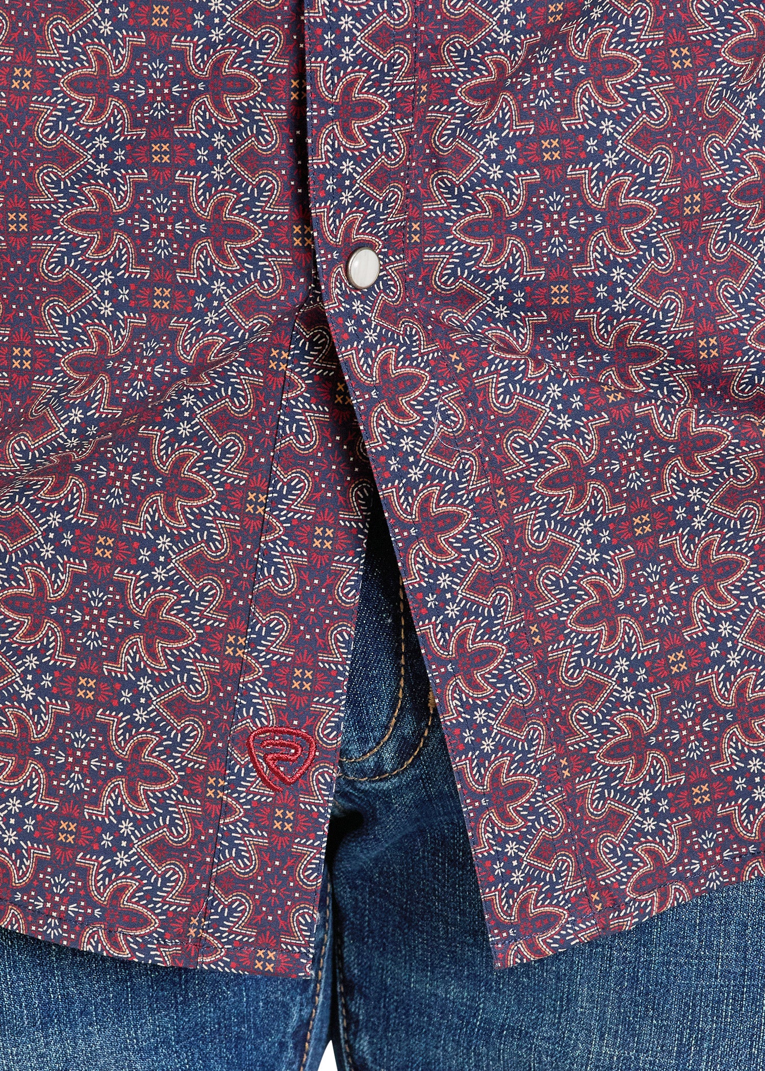 Close-up of a patterned shirt with a button and jeans in the background
