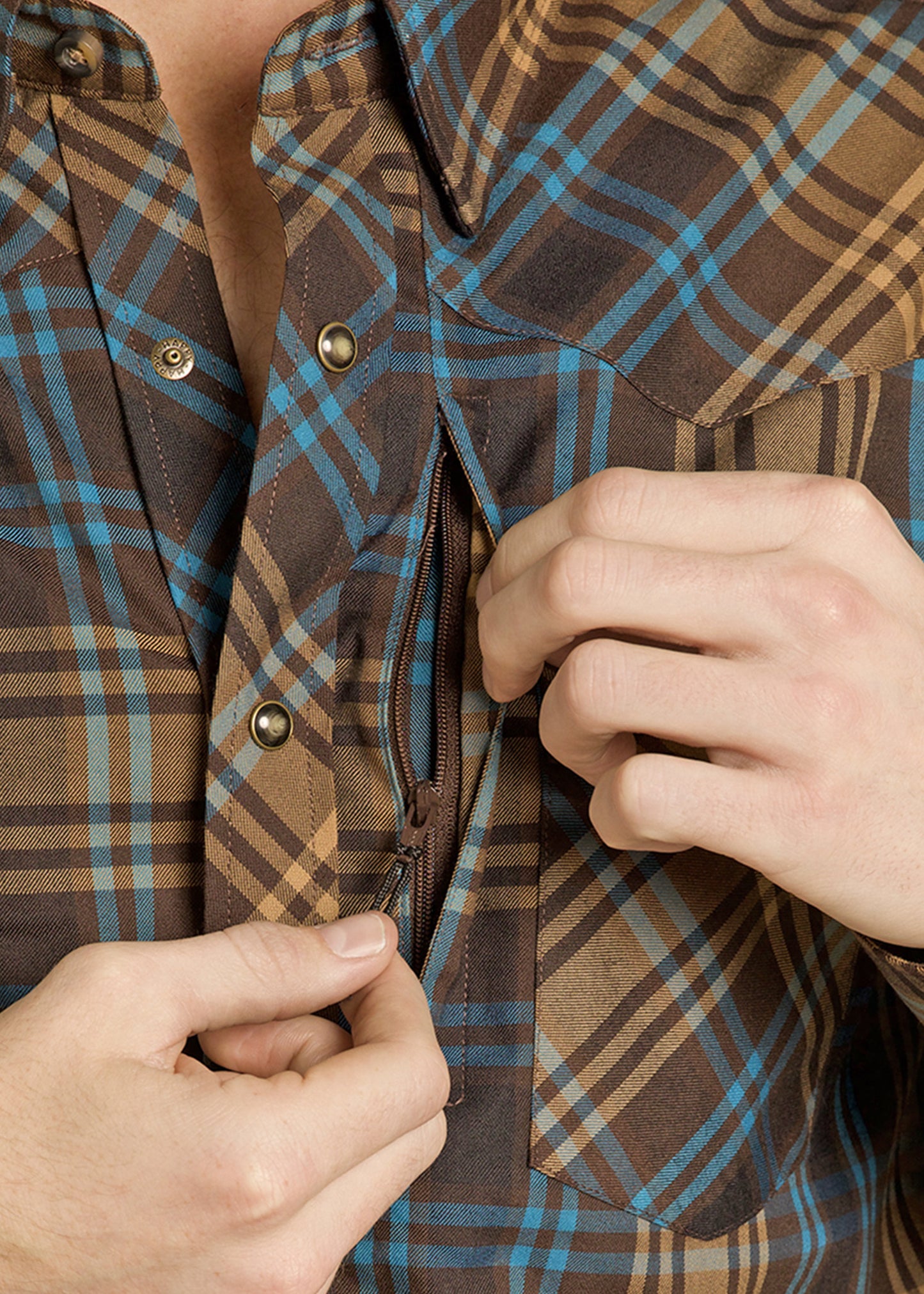 Close-up of a person adjusting the zipper on a brown and blue plaid jacket.