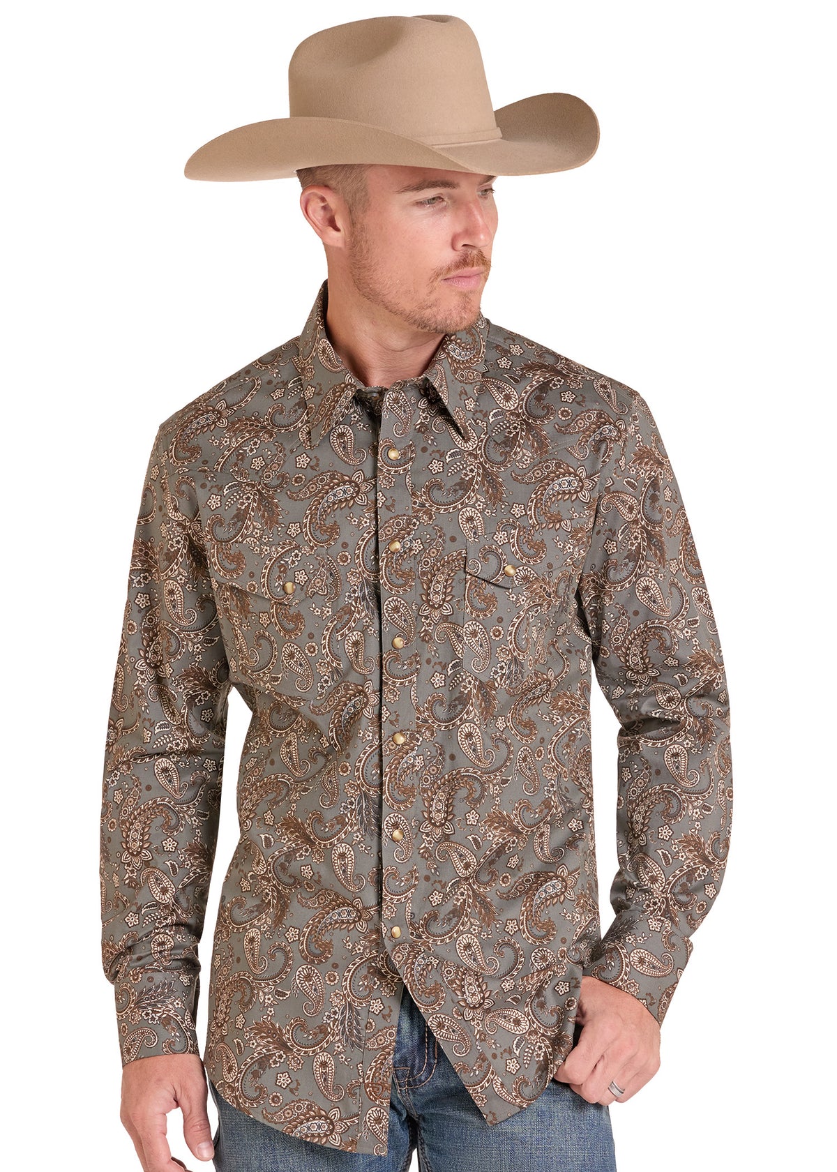 A man wearing a tan cowboy hat and a long-sleeve western button-up shirt with a brown and beige paisley pattern, paired with blue jeans, against a plain white background.