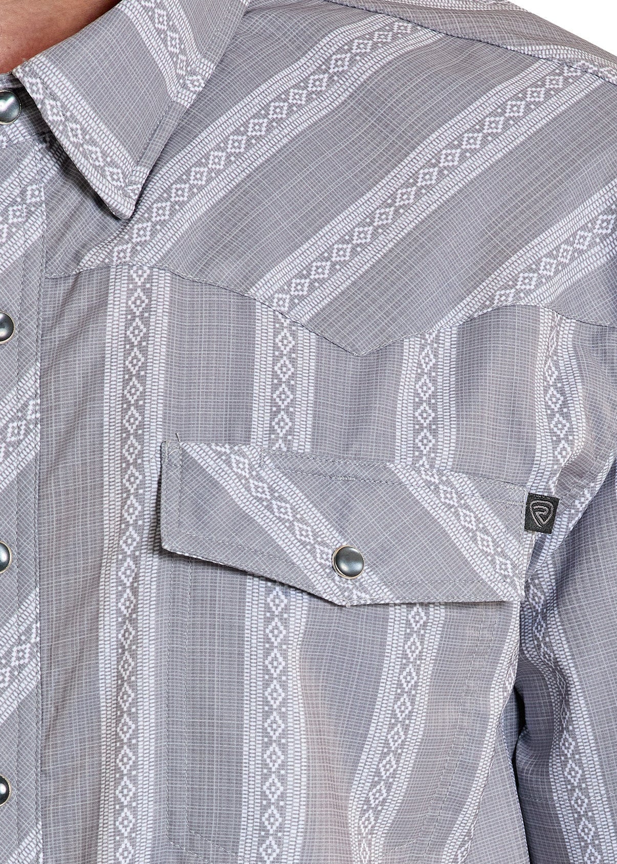 Close-up of a gray patterned shirt with a brand logo on a person wearing it.