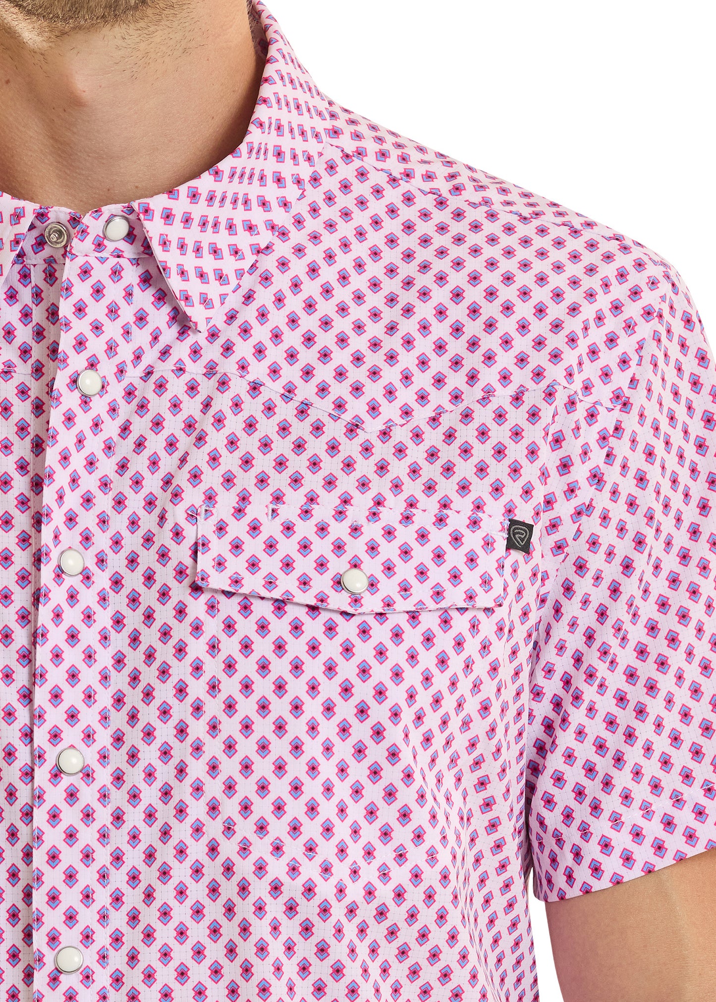 Close-up of a person wearing a pink patterned shirt with a brand logo on a white background
