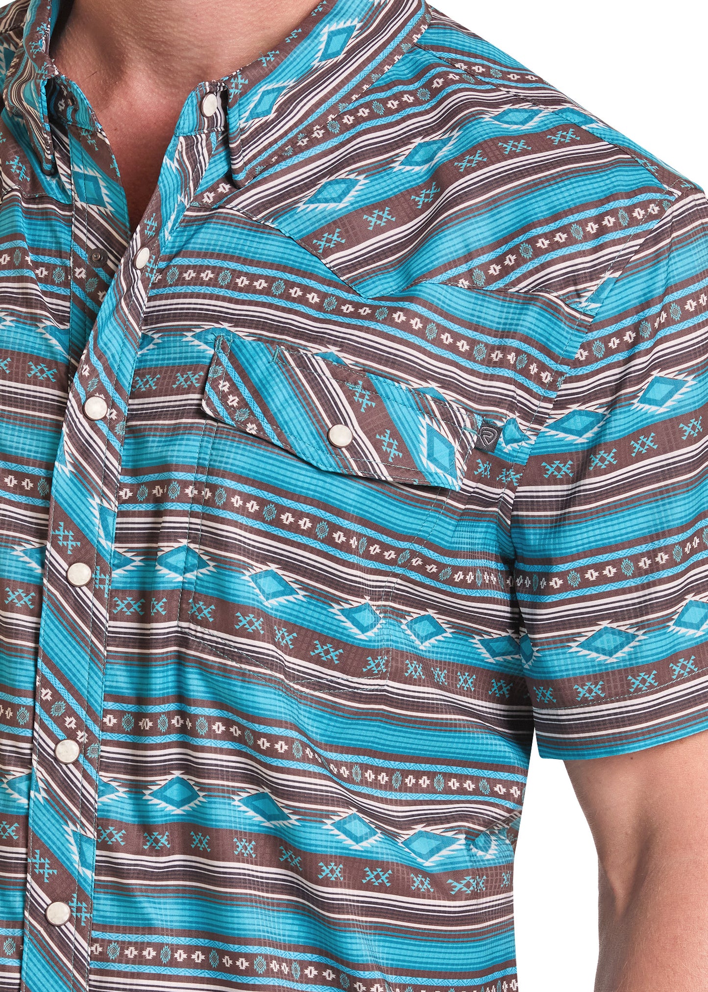 Close-up of a short-sleeve button-up shirt with a turquoise, brown, and white geometric pattern, worn by a model.