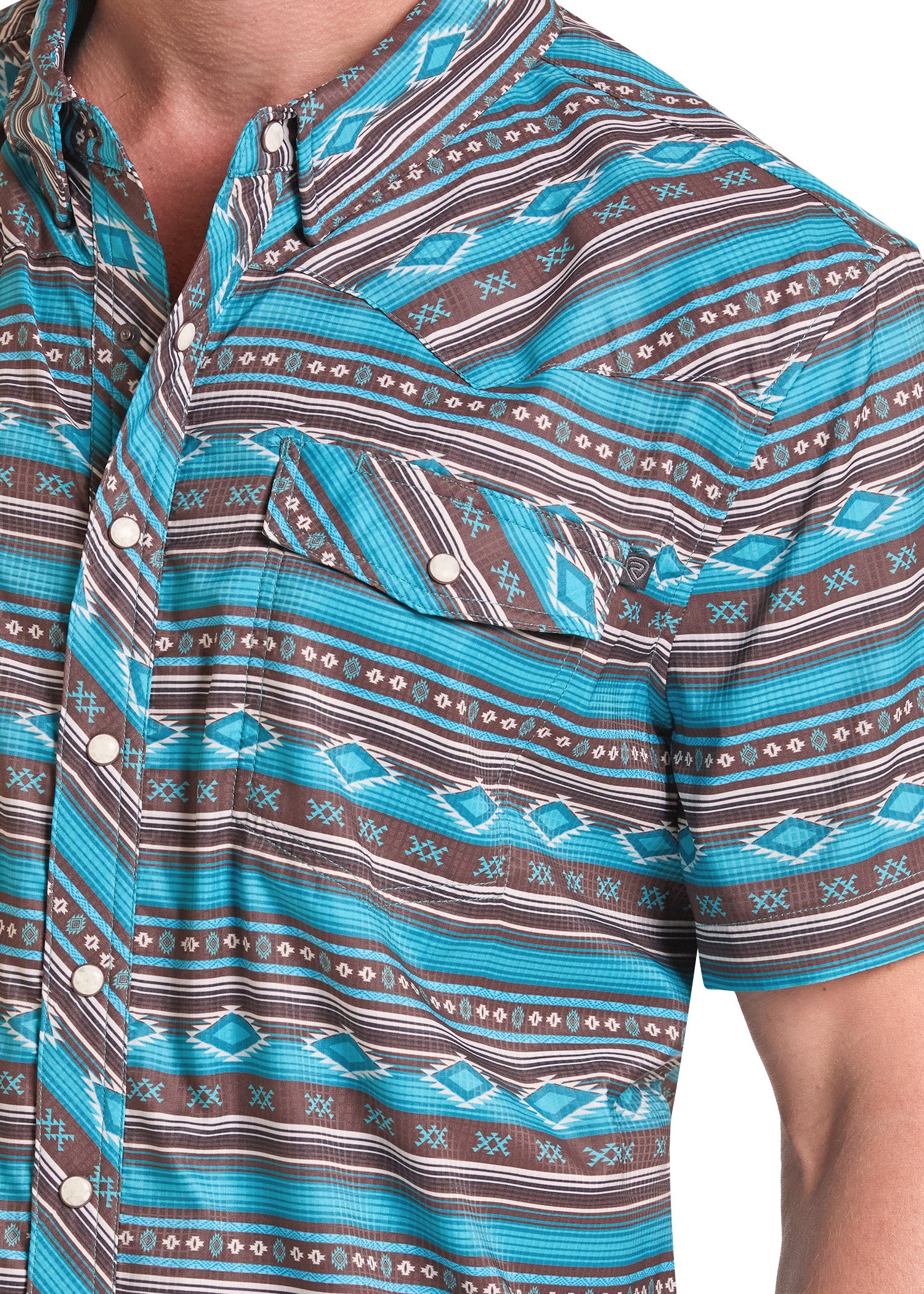 Close-up of a short-sleeve button-up shirt with a turquoise, brown, and white geometric pattern, worn by a model.