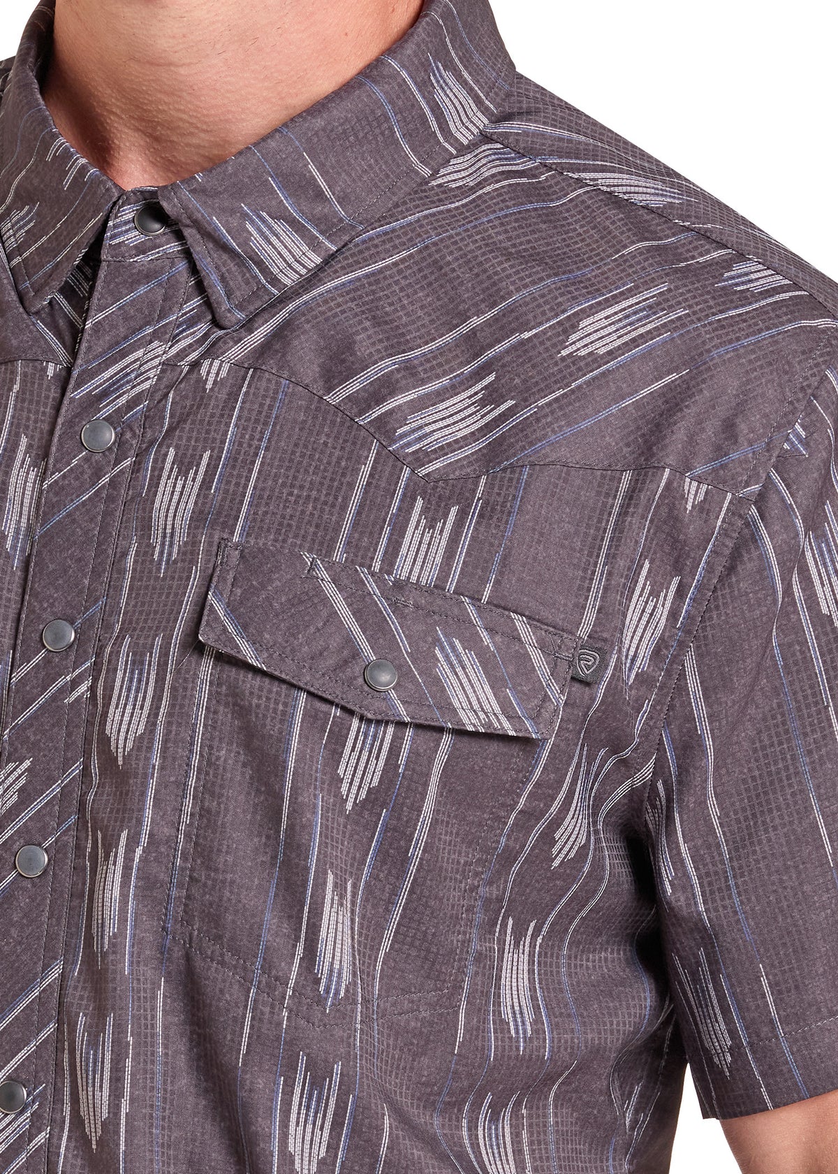 Close-up of a short-sleeve button-up shirt worn by a model, featuring a dark gray and brown base with a white abstract brushstroke pattern.
