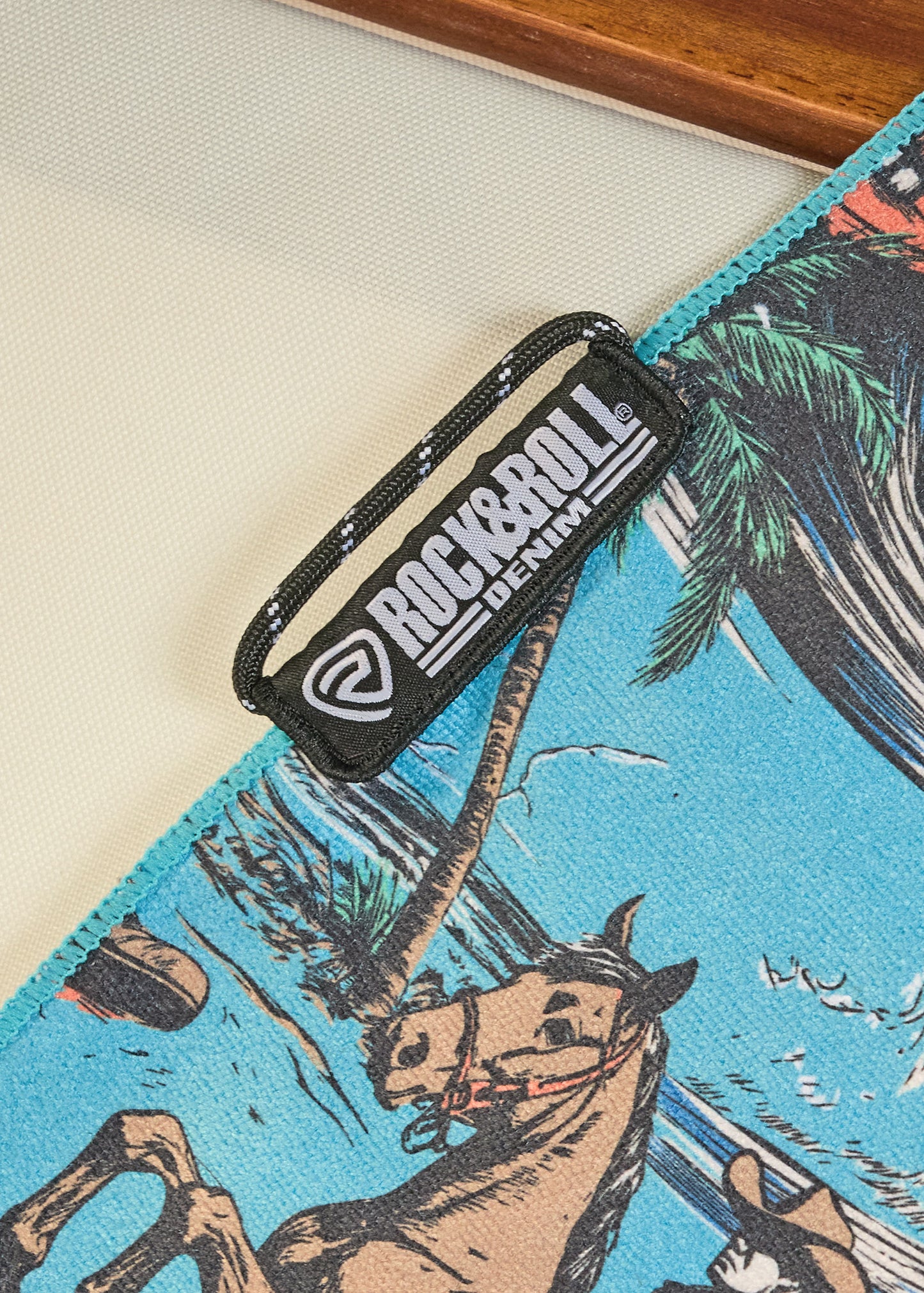 Black 'Rock & Roll' belt buckle on a blue fabric with horse and palm tree design.