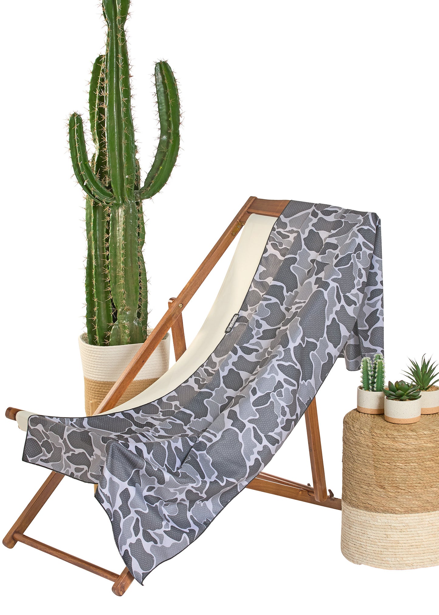 Gray patterned towel draped over a wooden chair with cacti in the background